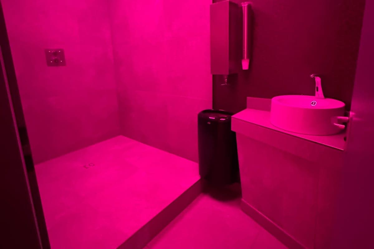 Modernes Bad mit Dusche und Waschtisch in Pink beleuchtet