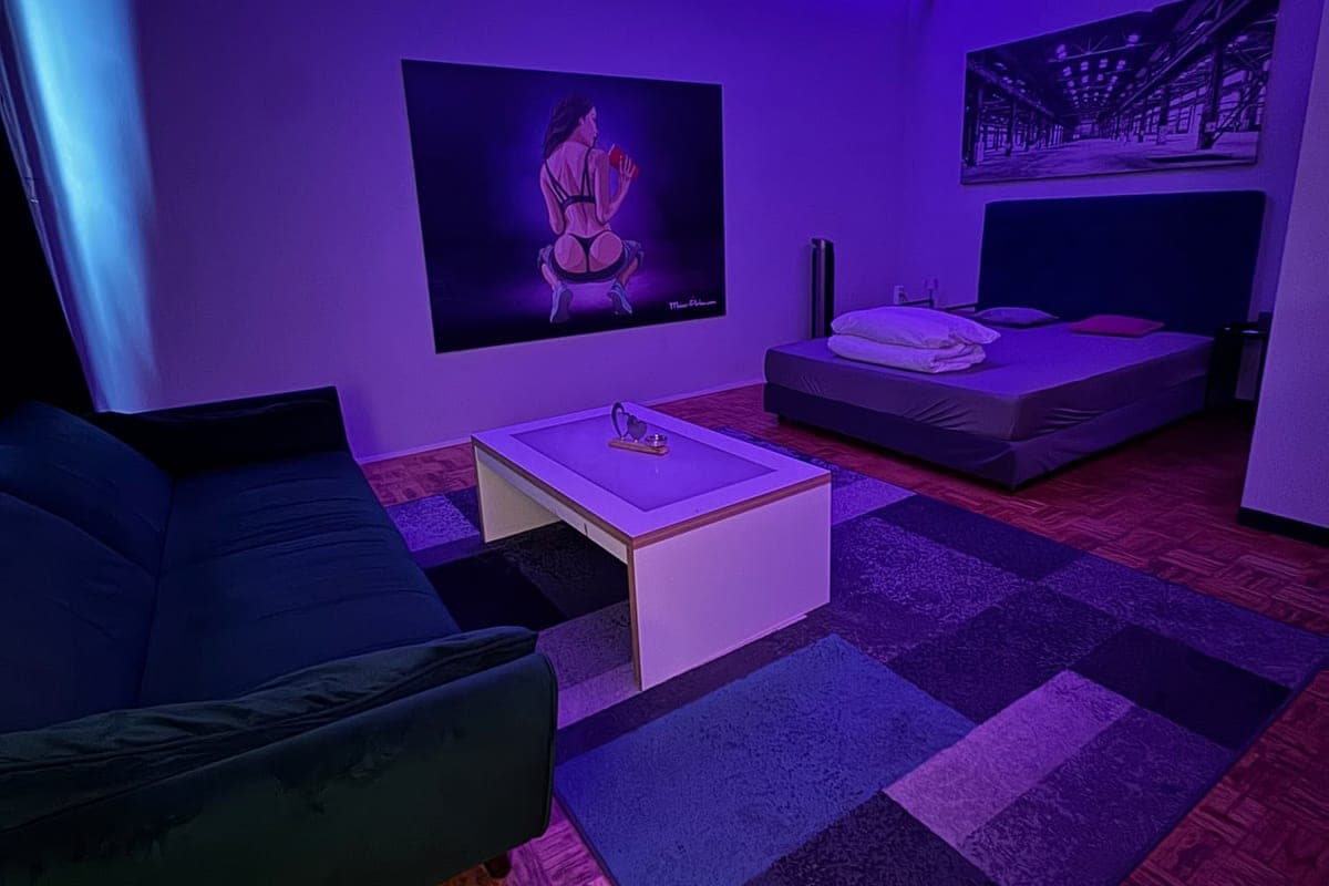 Zimmer mit lila Licht, Sofa und Doppelbett bei Meine Perlen