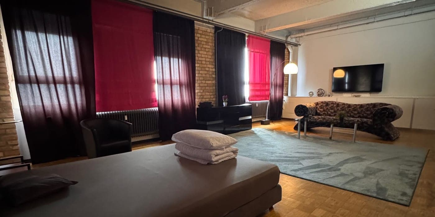 Großes Loft-Zimmer mit Bett, Lounge-Ecke und Industrie-Charme